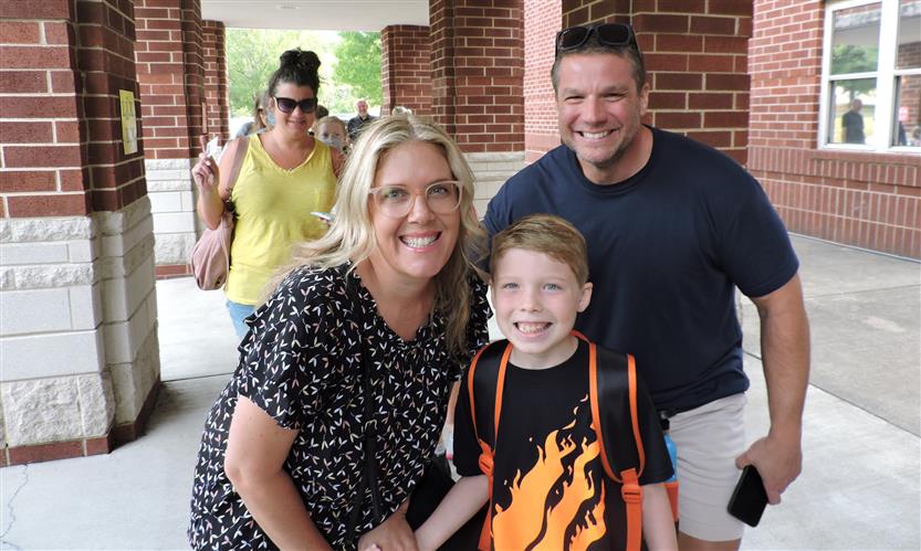 A family smiles before walking into school